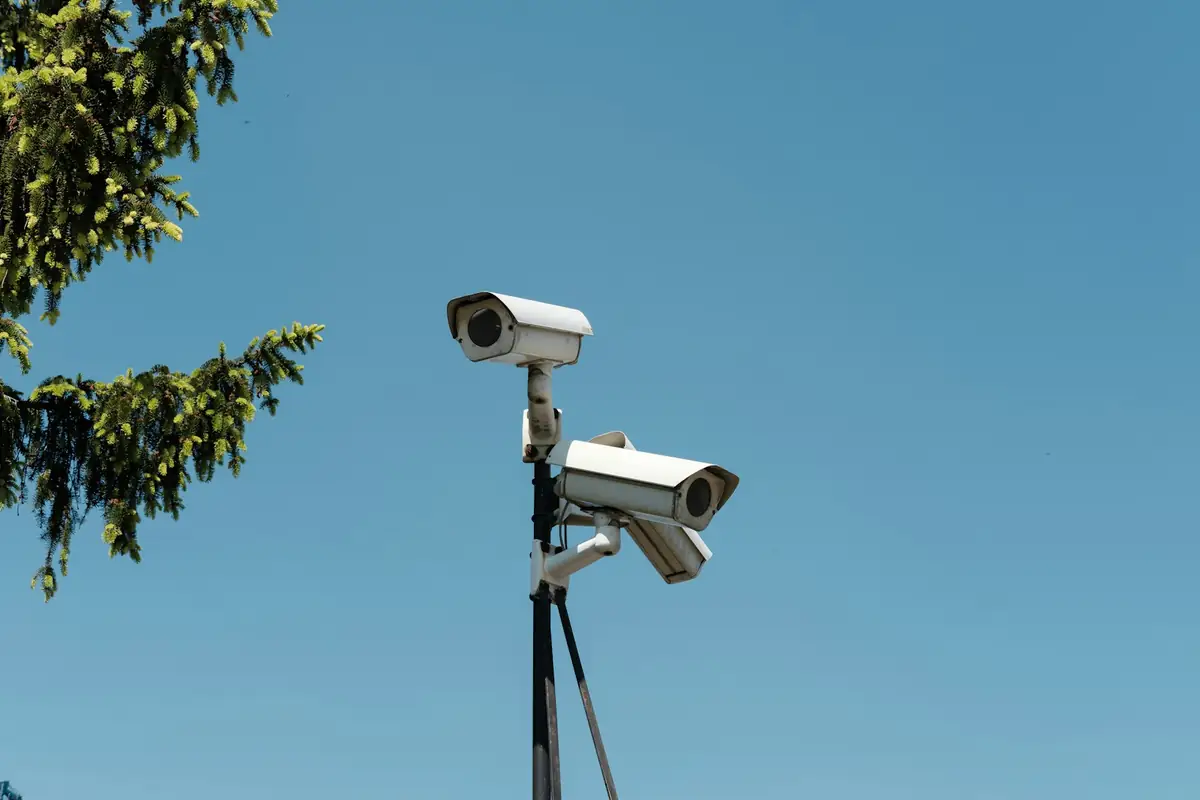 Two CCTV cameras mounted on a pole against a clear sky